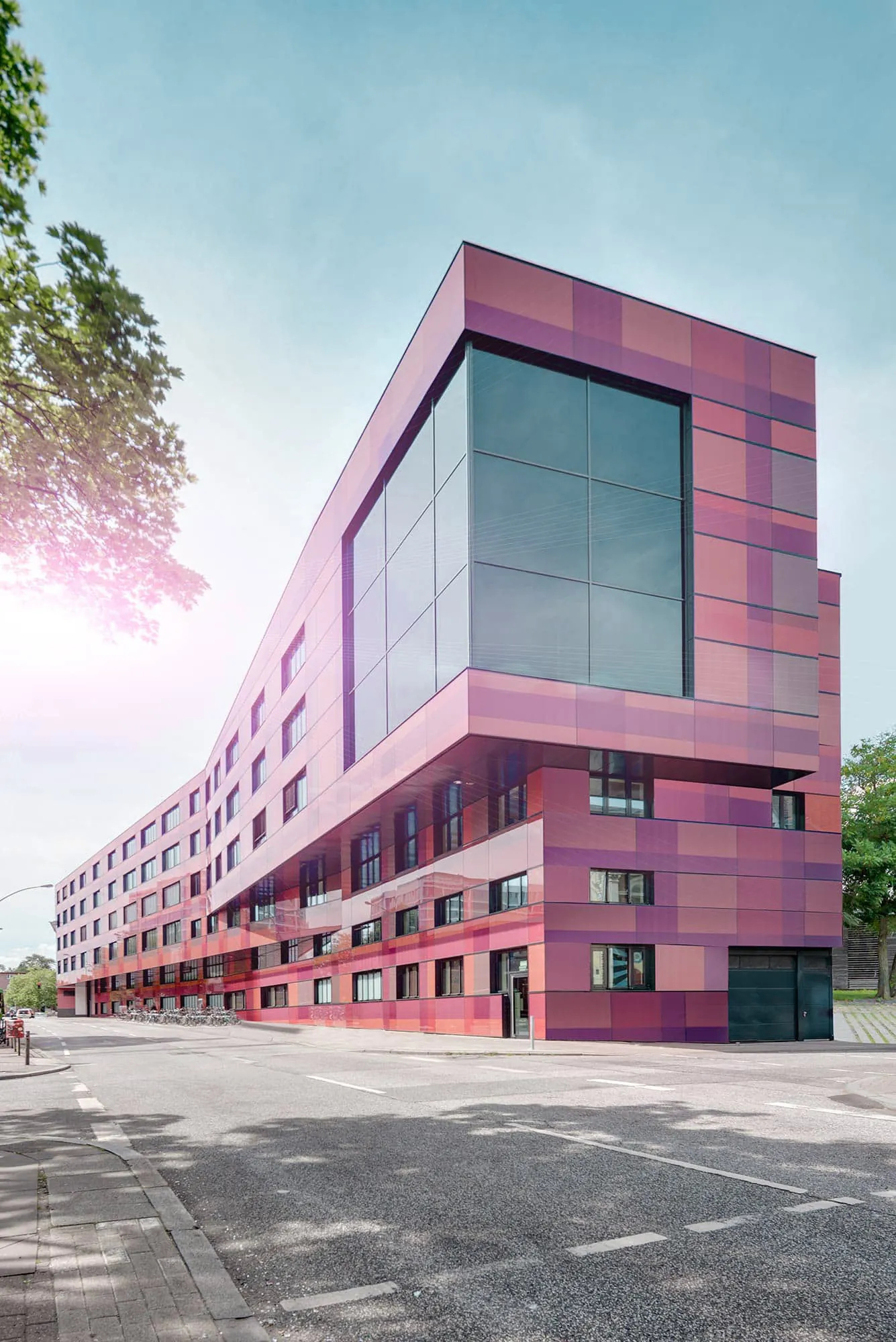 Rosa verkleidetes Eckgebäude mit großer Glasfront