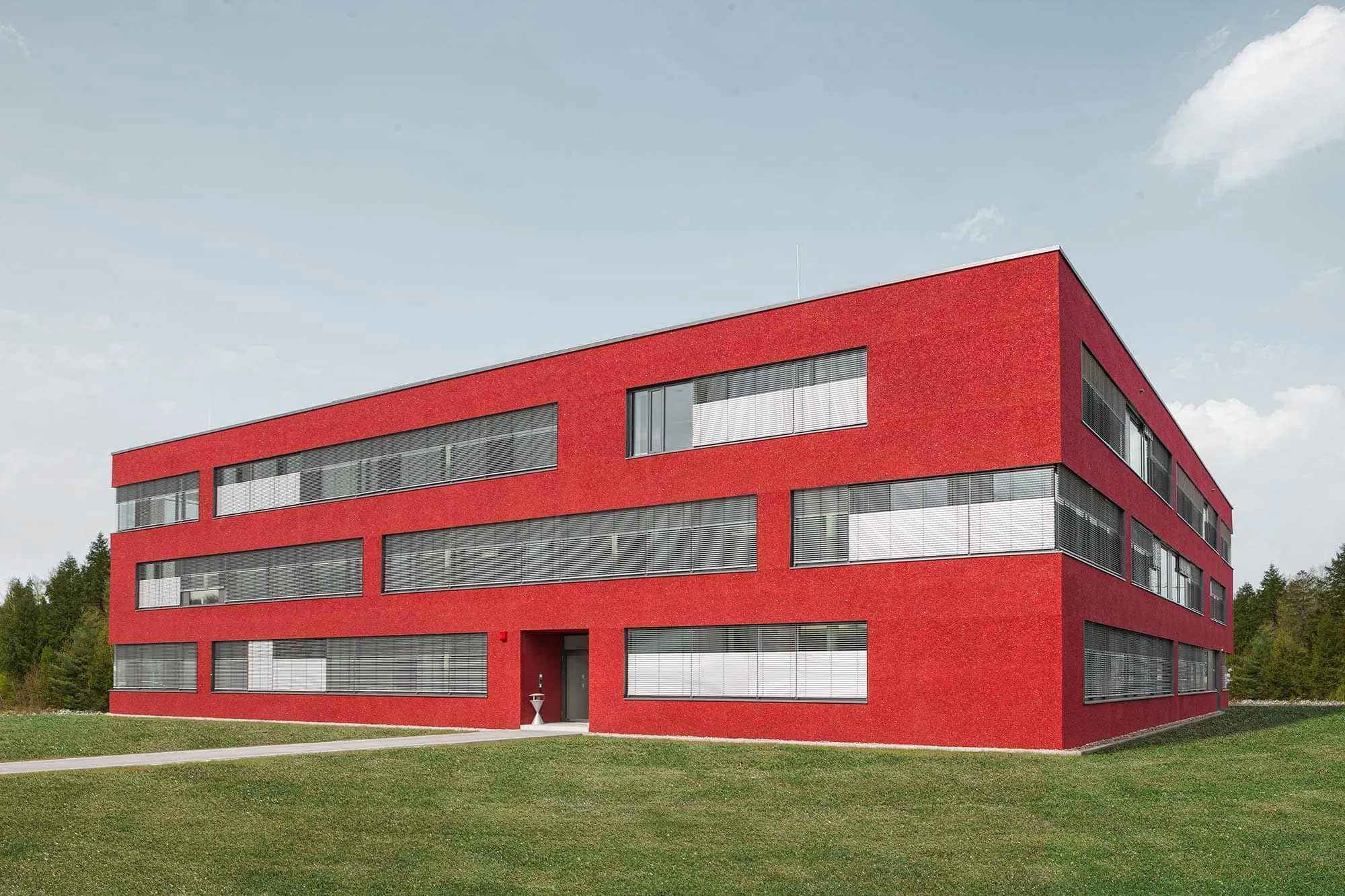 Rotes mehrgeschossiges Gebäude mit horizontalen Fensterbändern