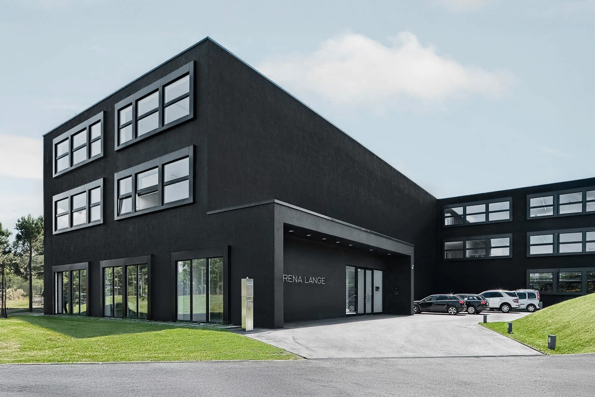 Schwarzes Bürogebäude mit regelmäßigem Fensterraster und zurückgesetztem Eingang