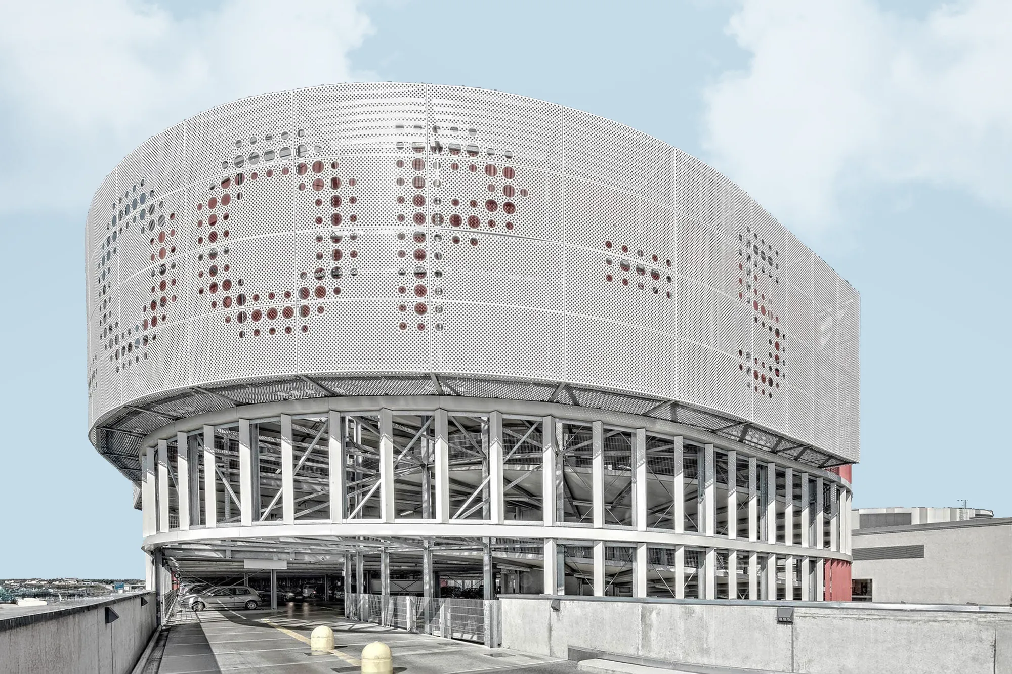 Rundes Gebäude mit heller perforierter Fassade und verglastem Sockel