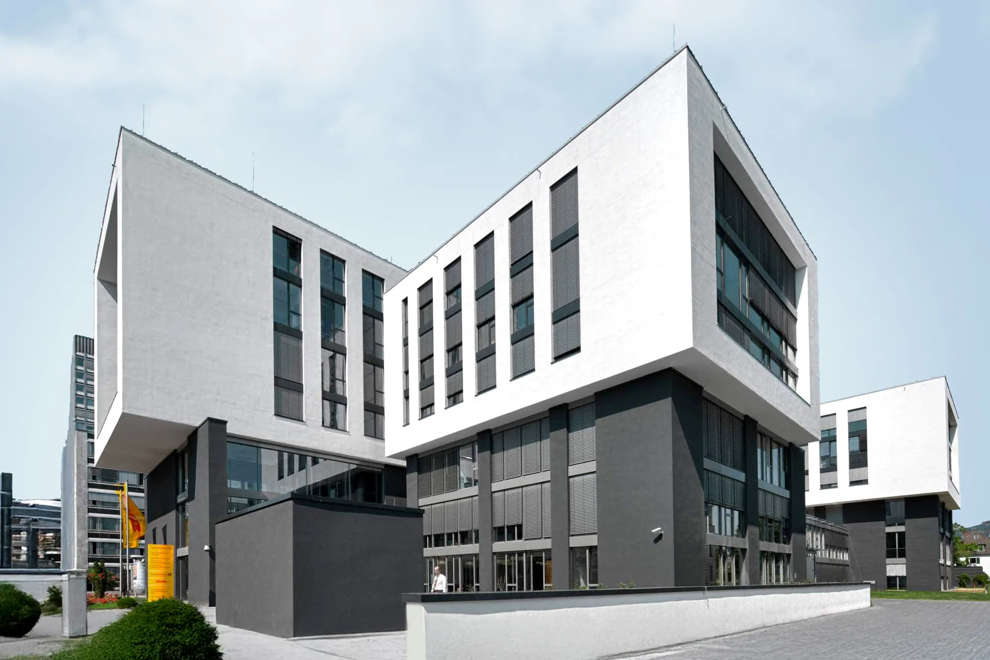 Modernes Eckgebäude mit weißen Fassadenrahmen und dunklem Sockel