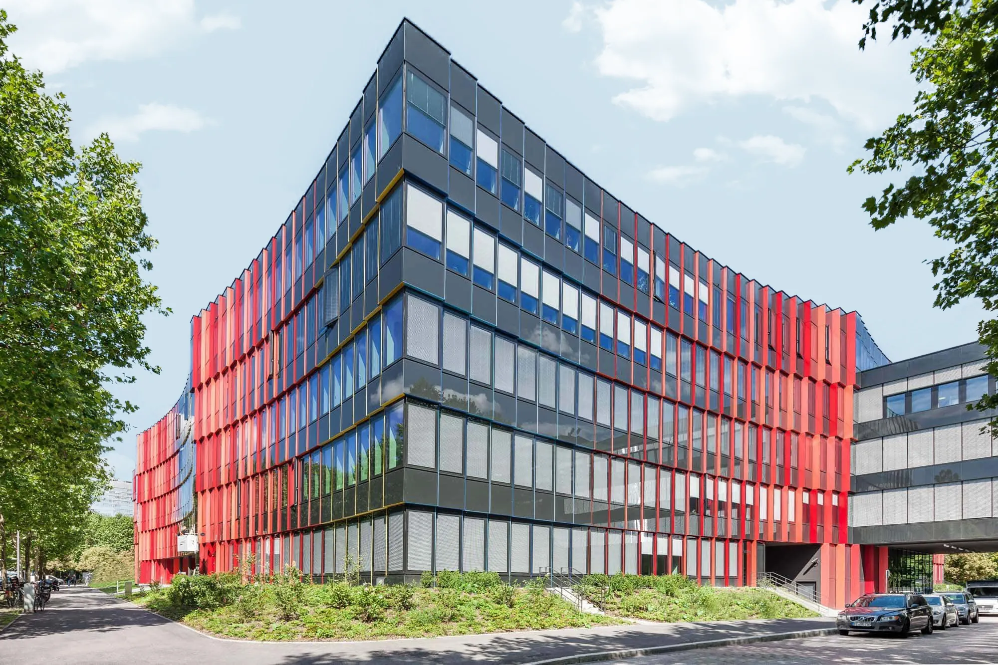 Bürogebäude mit dunklen Glasflächen und roten Fassadenlamellen