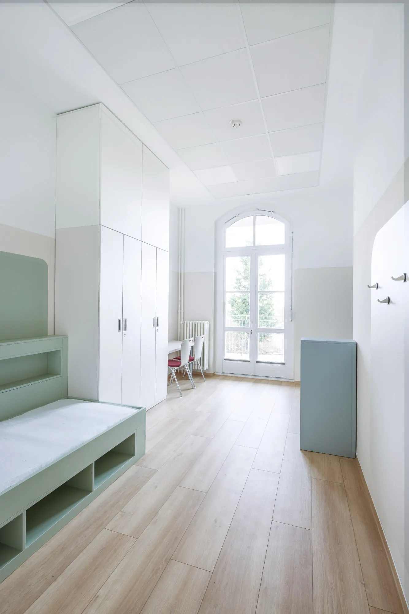 Heller Wohnraum mit Holzboden, Einbaumöbeln und hohen Fenstern