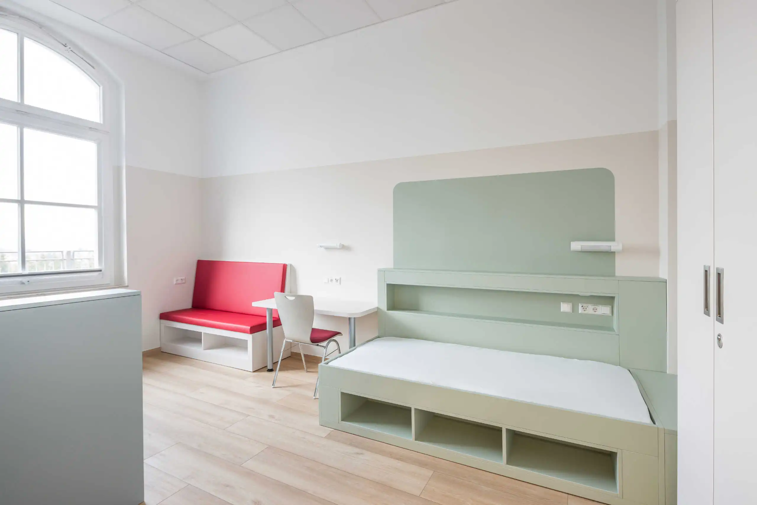 Heller Wohnraum mit Einbaumöbeln, Sitzbank und rotem Sofa