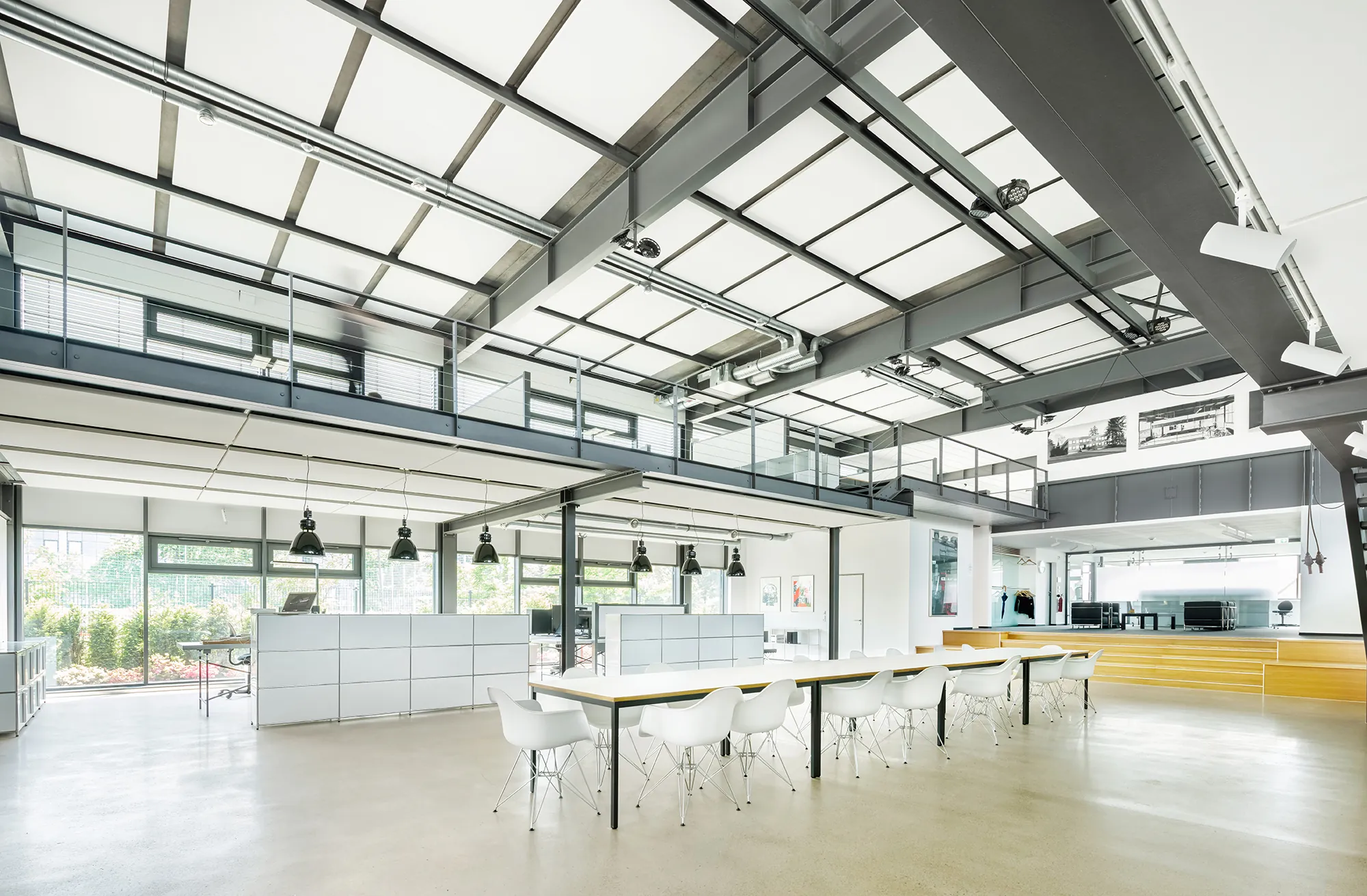 Große helle Halle mit Stahlträgern, Glasdach und offenen Arbeitsflächen