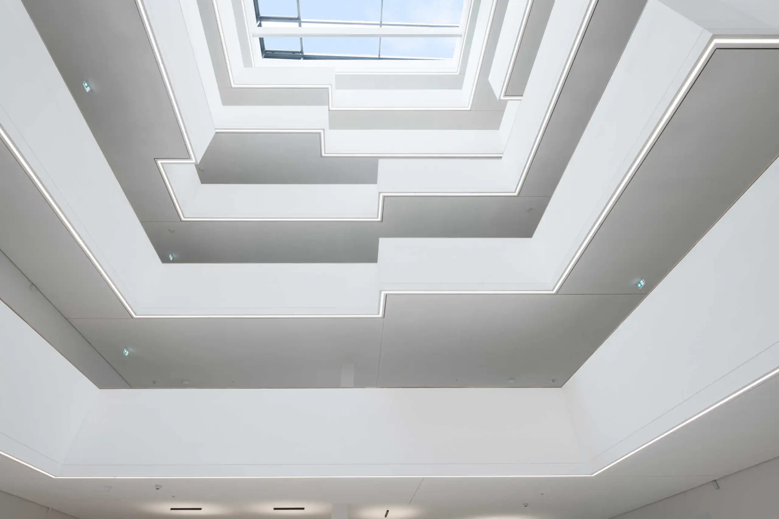 Blick nach oben durch versetzte weiße Atriumgalerien zum Glasdach
