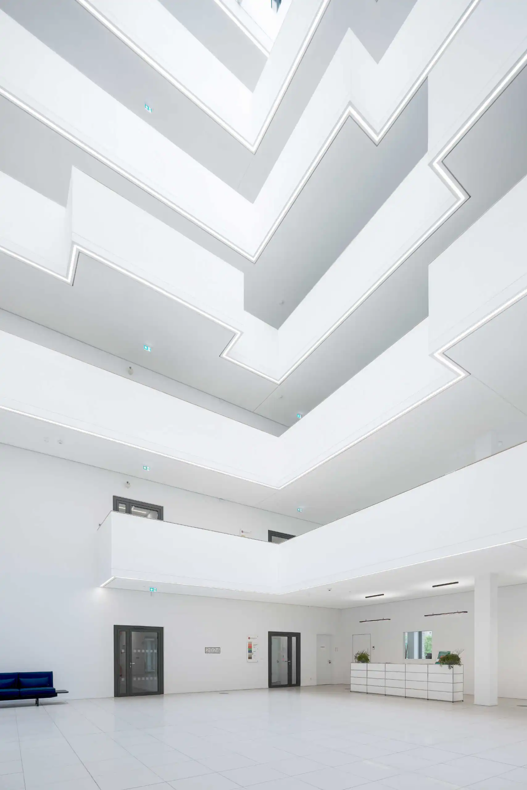Lichtdurchflutetes Atrium mit weißen Galerien und geometrischen Brüstungen